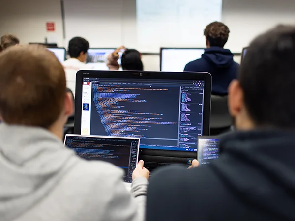 students entering code on a laptop, earning computer science degree