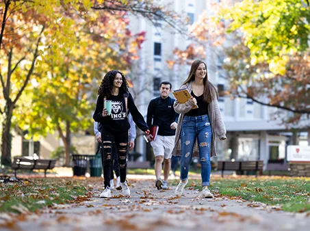 students walking outdoors in fall weather, showing inclusion is still important to a Catholic university