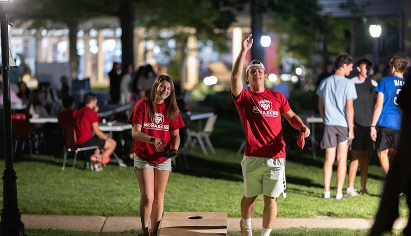 two students playing cornhole, an activity part of college life