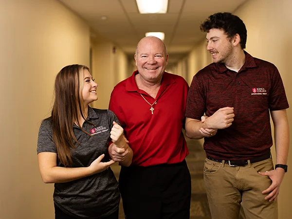 elderly person walking with the help of two doctor of occupational therapy students