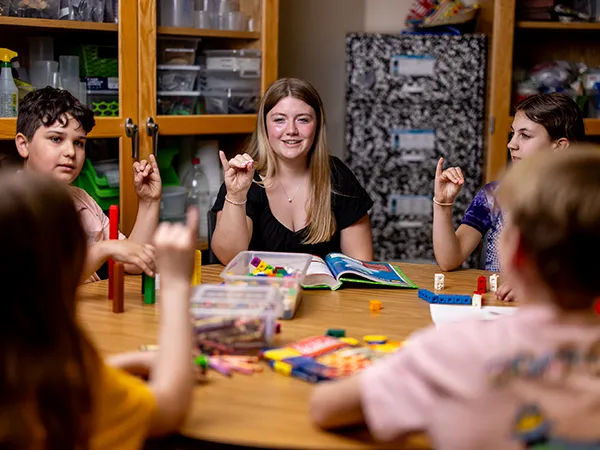 a teacher with a bachelor in special education in a classroom table with a group of children